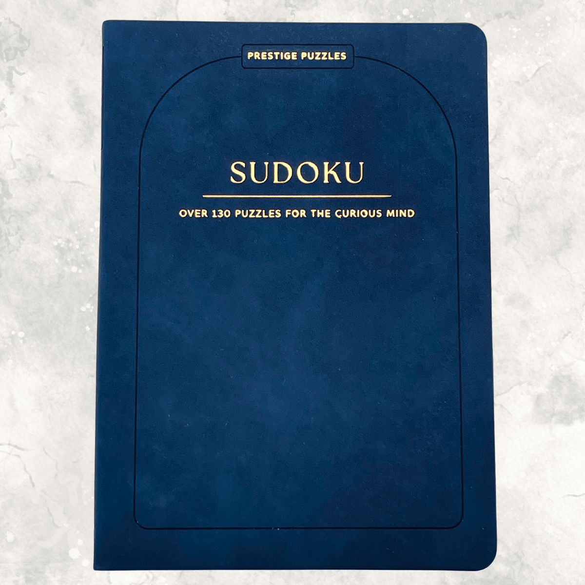 Navy blue faux suede Sudoku puzzle book featuring over 130 puzzles for the curious mind