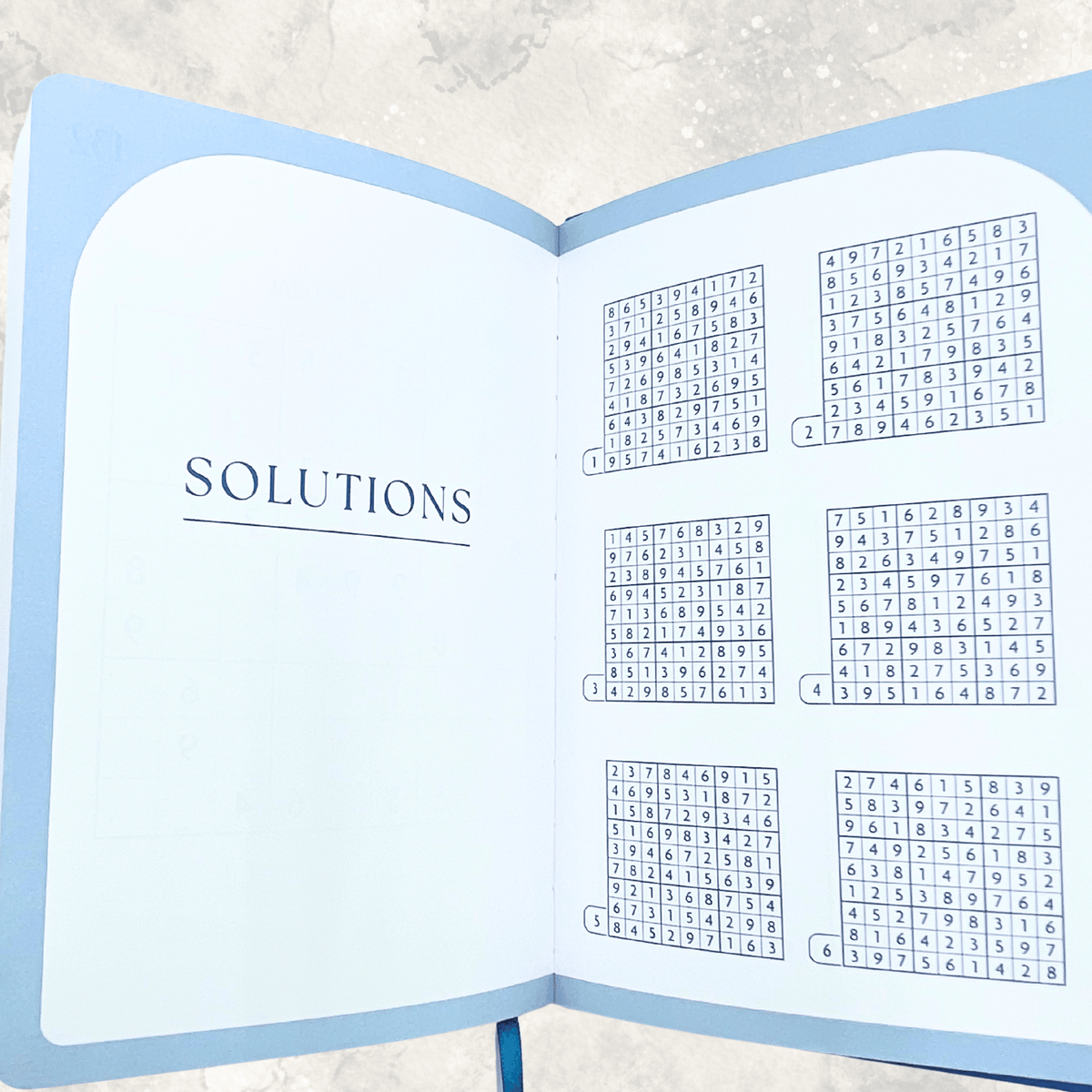 Sudoku puzzle book opened to the solutions section with answers to verify completed puzzles