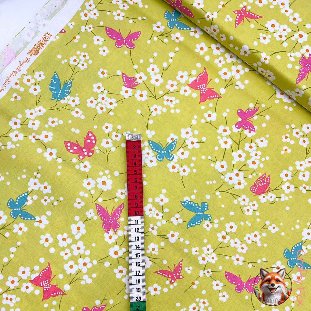 Measuring tape showing Butterfly Blossom fabric, showing size of blue butterfly