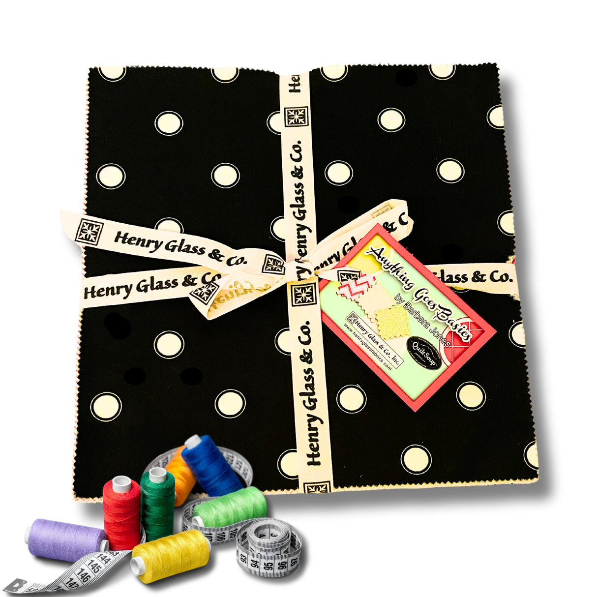 Threads and tape measure in foreground with Layer cake fabric pack