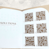 Open crossword puzzle book showing completed crossword grids in the solutions section