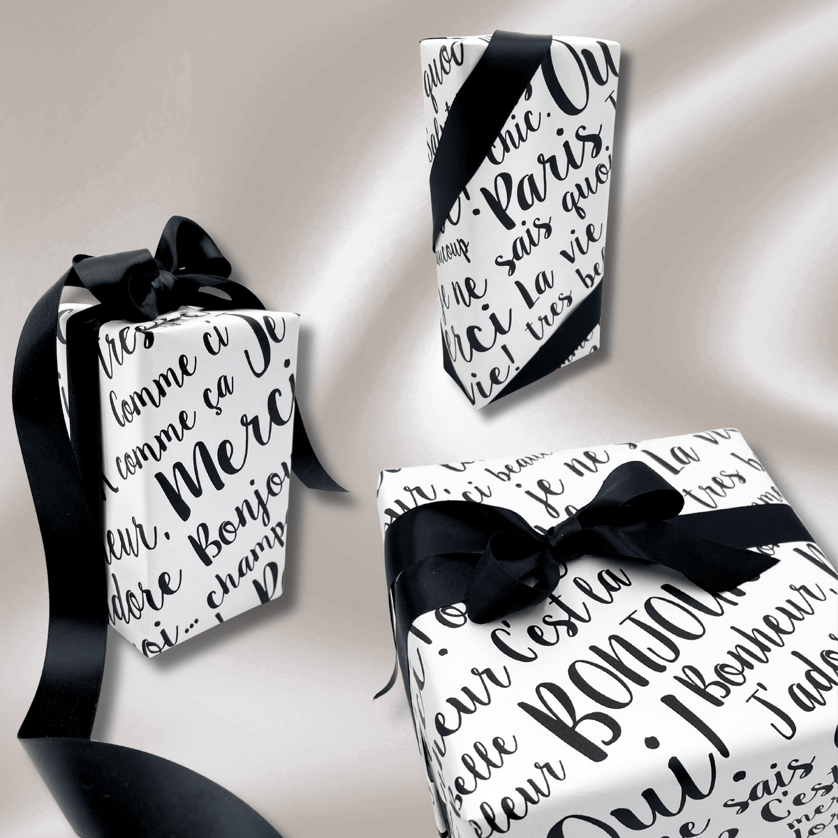 Collection of beautifully wrapped gifts featuring Paris black and white pearlised wrapping paper with luxurious black satin ribbon.