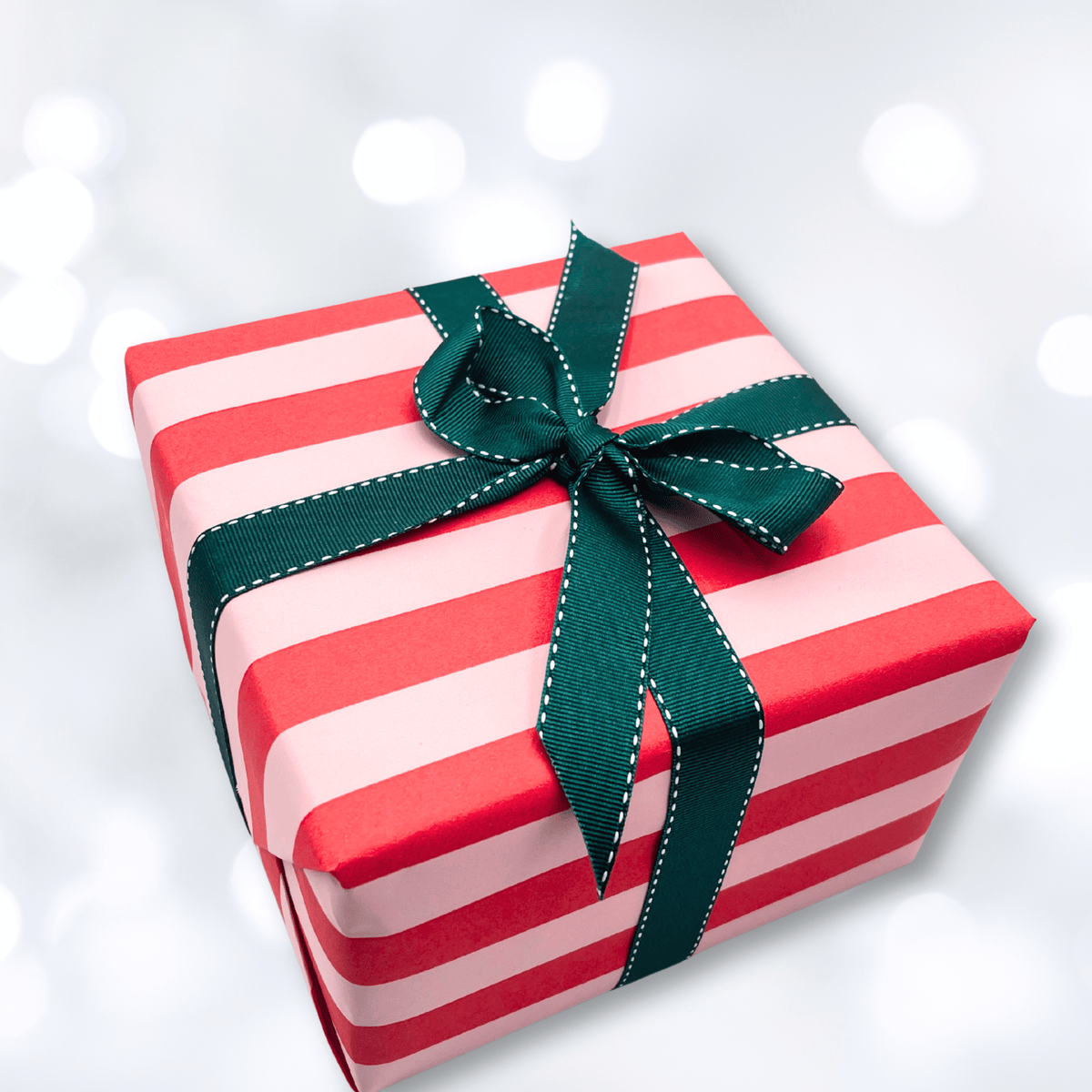 Christmas gift wrapped in Pavilion Poppy red and pink striped paper with a dark green grosgrain ribbon bow