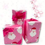 Three pink Christmas gift boxes with Santa Claus and white cloud wrapping paper, tied with bright pink satin ribbons, on a white background with faint snowflakes and decorative bows.