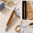 Handcrafted two-tone wooden seam ripper with chrome fittings, shown with sewing fabric, thread and detailed blade close-up.