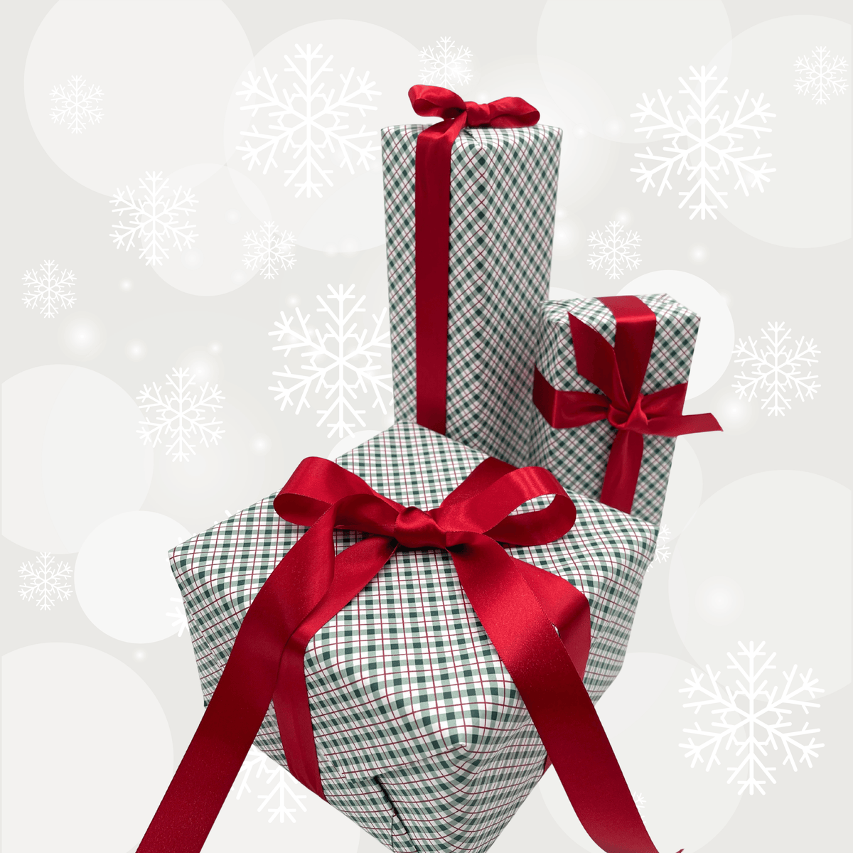 Three wrapped gift boxes with red ribbon bows and a green-and-white checkered pattern, arranged together against a light gray holiday background with snowflakes.