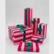 Collection of Christmas presents wrapped in red and pink Pavilion Poppy striped gift paper with contrasting dark green ribbon bows